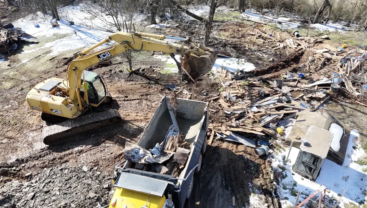 Laser Level Dirt Works excavator loading demolition debris into a dump truck